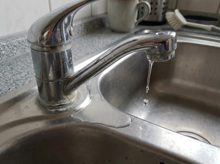 Tropfende und korrodierte Rohrverbindung unter einem Waschbecken